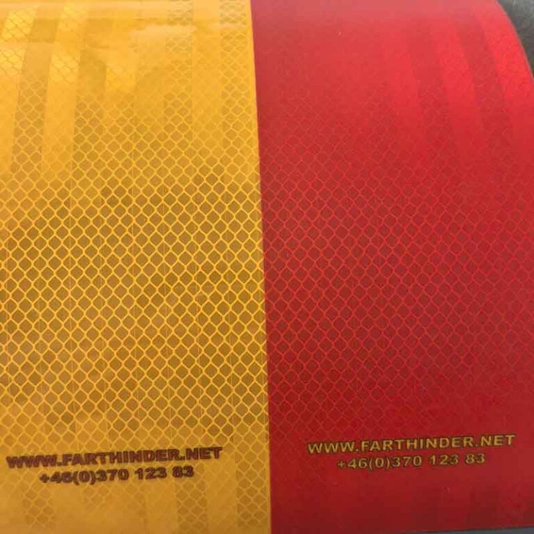 Närbild av högprismatisk reflextejp i rött och gult med bikakemönster och texten www.farthinder.net