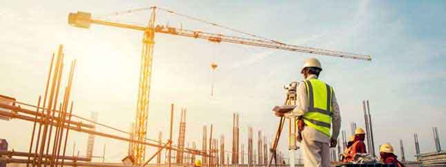 Byggarbetsplats med kran och byggarbetare som arbetar med mätutrustning vid ett större byggprojekt