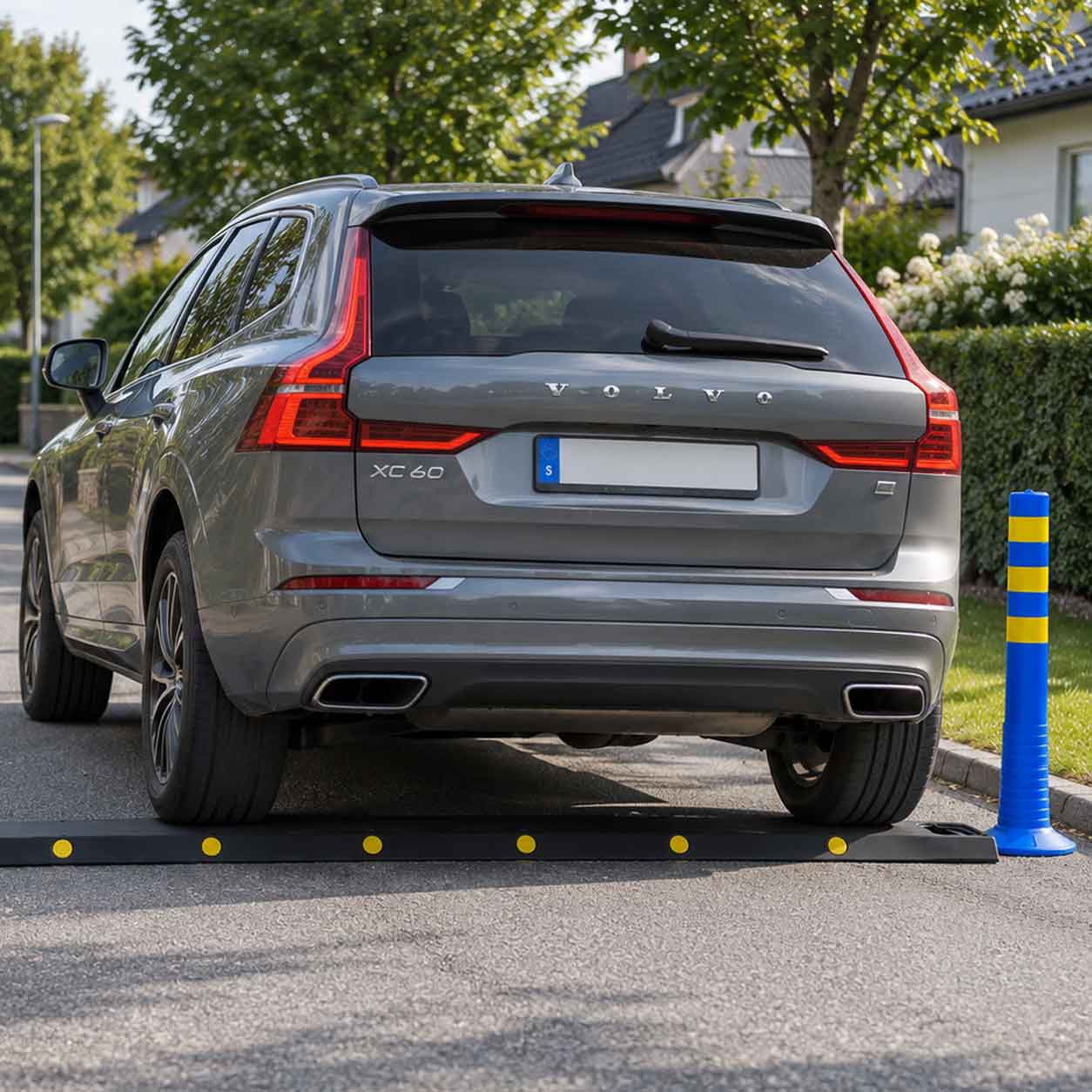 Bil kör över portabelt farthinder med blå markeringsstolpar på villagata