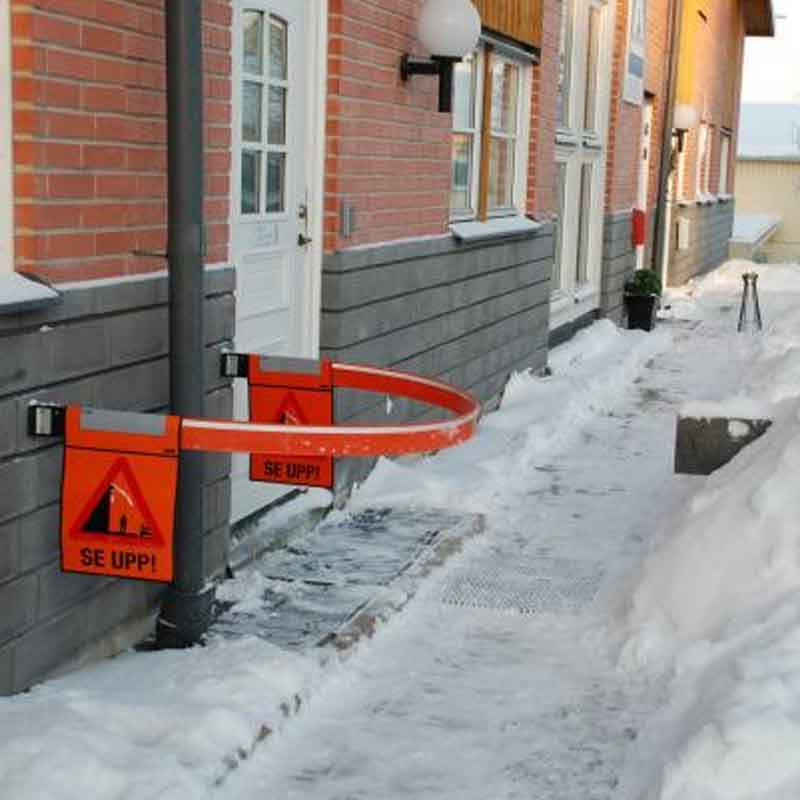 Lång varningsbom för snöras och isras som spärrar av trottoar vid fastighet vintertid