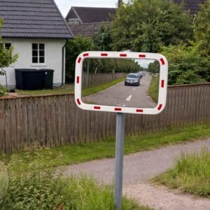 Trafikspegel med röd reflexram vid cykelbana som visar mötande bil i spegelbilden