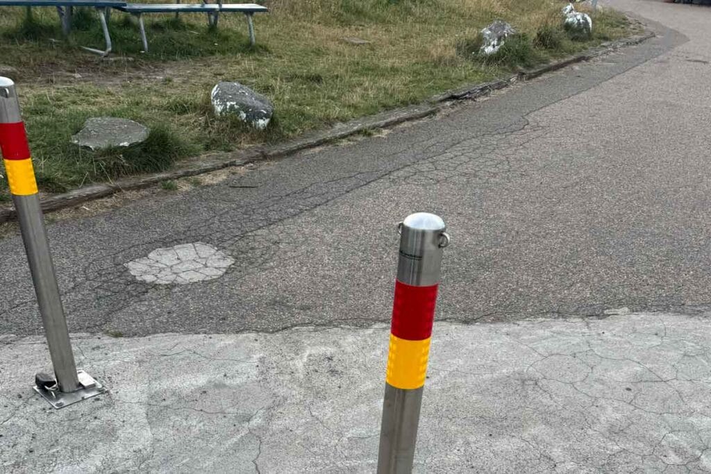 Rostfria avspärrningspollare med röda och gula reflexer monterade vid en väg i Torekovs hamn.