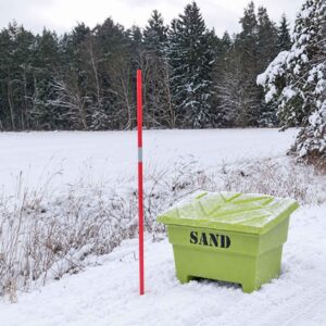 Grön sandlåda och rödvit snökäpp i snötäckt vintermiljö